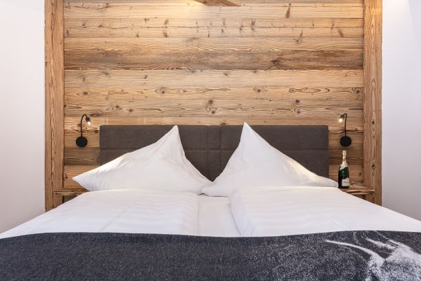 Doppelbett vor Altholzwand in der Klamm Lodge