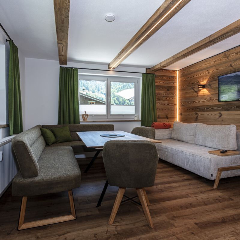 Wohn- und Essbereich der Klamm Lodge mit Altholzwand